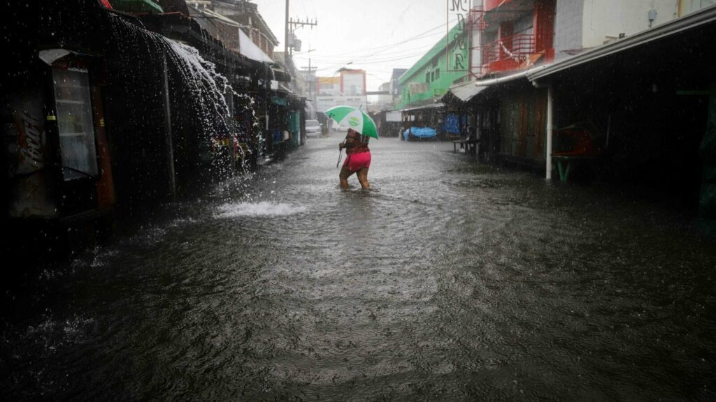 A woman walks along a flooded street during the passage of tropical storm Sara in La Ceiba, Honduras, on November 15, 2024. Honduras' President Xiomara Castro said emergency services had been activated to deal with 'damage already caused by the rains,' warning that Sara's impacts 'could become a catastrophic event.' (Photo by AFP)