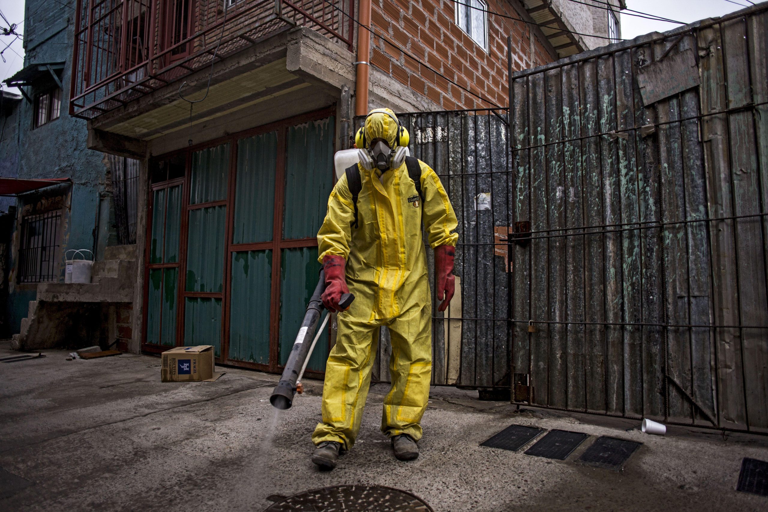 person in yellow protective suit using fumigator