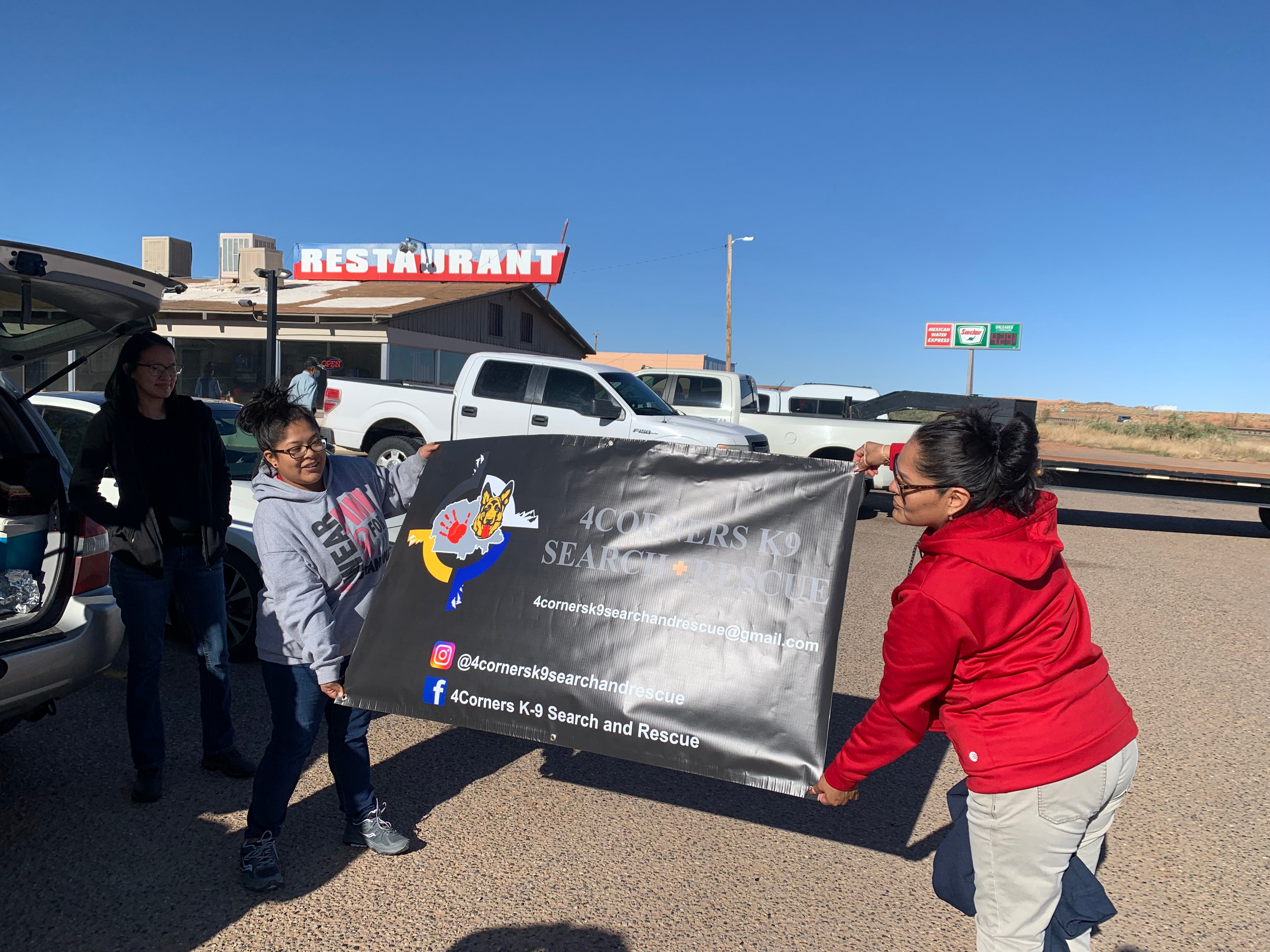 Volunteers with Four Corners K9 Search and Rescue unfurl a new banner before a search for a missing person on the Navajo Nation on April 23rd, 2022.