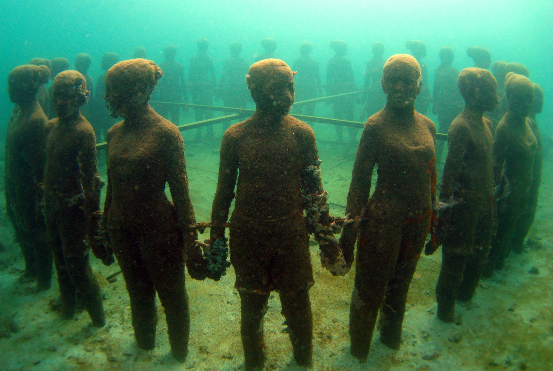 A circle of sculptures of people holding hands sits under the sea in Grenada. 