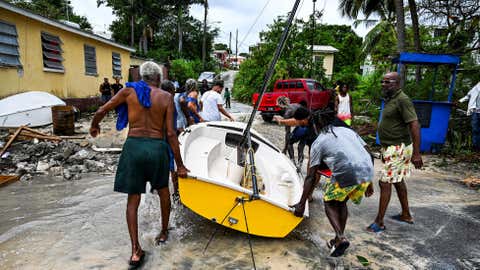 Residents clear a boat from the street as it gets flooded after the passage of Hurricane Beryl in the parish of Saint James, Barbados, near Bridgetown on July 1, 2024. Officials in Barbados said the island was buffeted by high winds and pelting rain, but appeared to have avoided disaster, reporting no injuries so far. (Chandan Khanna/AFP via Getty Images)