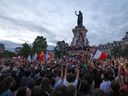 People wave French national tricolours during an election night rally following the first results of the second round of France's legislative election, at Place de la Republique in Paris on July 7.