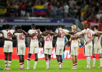 Canada players link arms before a shootout during a Copa America quarterfinal soccer match between Venezuela and Canada, Friday, July 5, 2024, in Arlington, Texas.