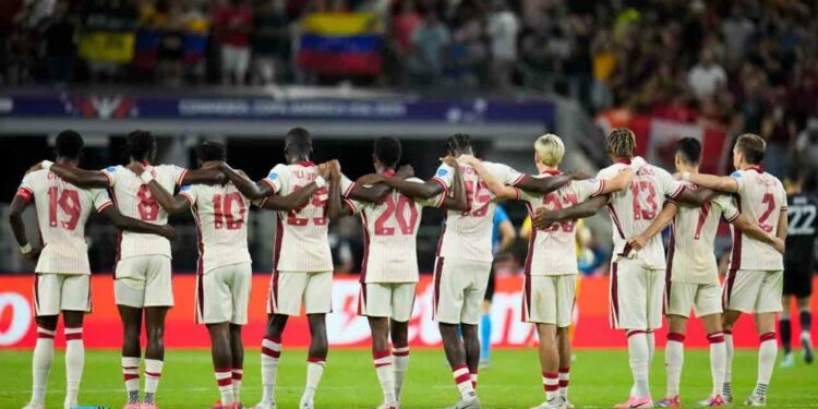 Canada players link arms before a shootout during a Copa America quarterfinal soccer match between Venezuela and Canada, Friday, July 5, 2024, in Arlington, Texas.