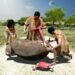 3D rendering of a prehistoric butchery event featuring three early humans processing a large animal carcass in a grassy landscape