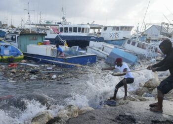 Fishermen pull a boat damaged by Hurricane Beryl back to the dock at the Bridgetown Fisheries in Barbados, Monday, July 1, 2024.