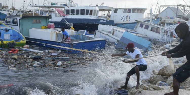 Fishermen pull a boat damaged by Hurricane Beryl back to the dock at the Bridgetown Fisheries in Barbados, Monday, July 1, 2024.
