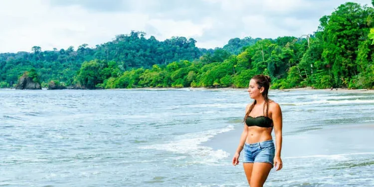 Female Tourist Walking Into The Ocean In Costa Rica, Central America