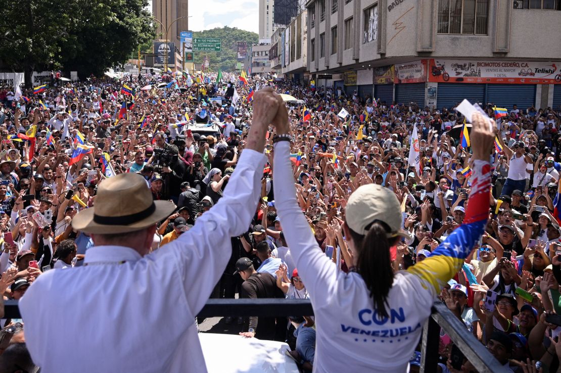 Venezuelan opposition presidential candidate Edmundo Gonzalez and opposition leader Maria Corina Machado hold hands at a presidential election campaign rally in Valencia, Carabobo State, Venezuela, on July 13, 2024.