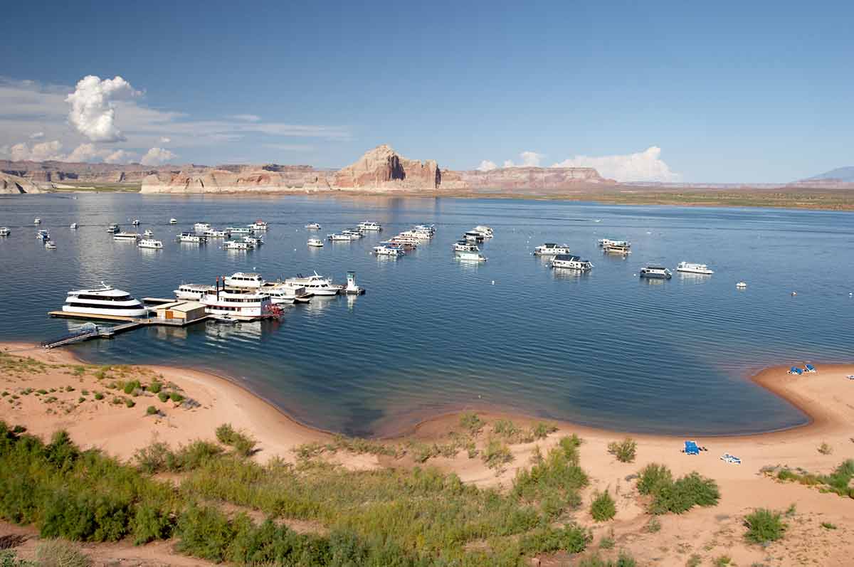 beaches in arizona boats anchored in the lake, a sandy beach and rock formations in the distance