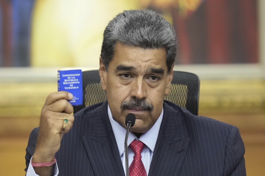 Venezuelan President Nicolas Maduro holds a small copy of the constitution as he gives a news conference at Miraflores presidential palace in Caracas, Venezuela, Wednesday, July 31, 2024, three days after his disputed reelection. (AP Photo/Matias Delacroix)