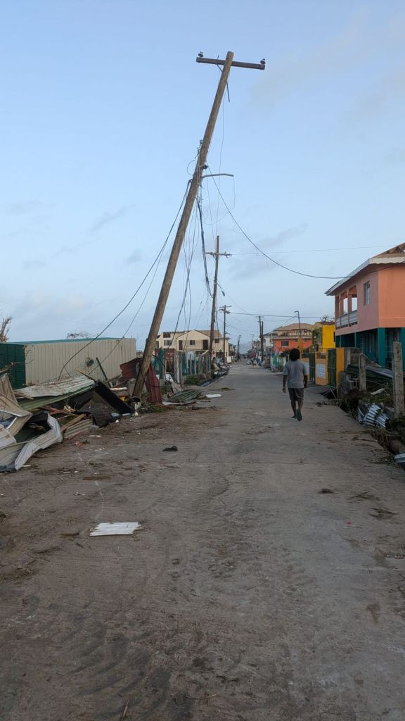 A photo of a man walking down a street where there is debris everywhere. 