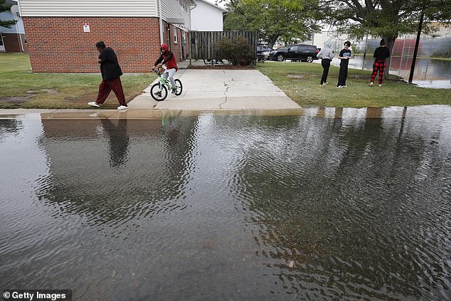 Neighbors survey flooded streets outside their apartments following two days of heavy rains from a tropical storm in Crisfield, Maryland