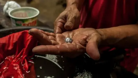 Getty Images A miner holds a piece of gold in his hand, still chemically bonded to mercury