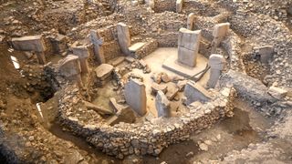 a circular ring of stones with pillars sticking up around it. it is surrounded by ancient rubble