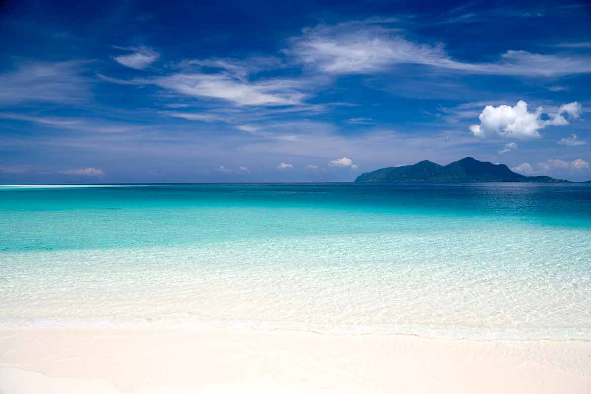 the best beaches in malaysia beach with deep blue skies, crystal clear waters and an island in the background