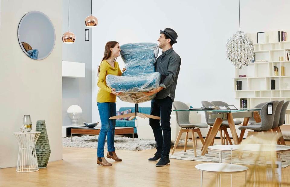 Happy couple carrying new arm chair