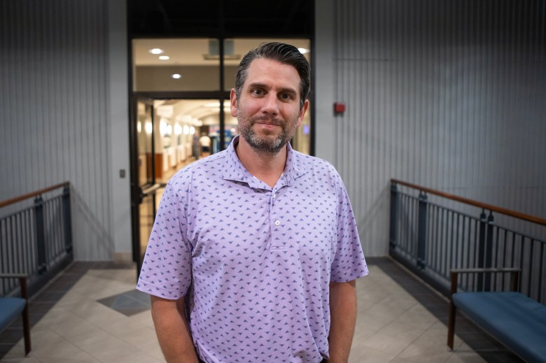 A person in a purple shirt stands outside an office.