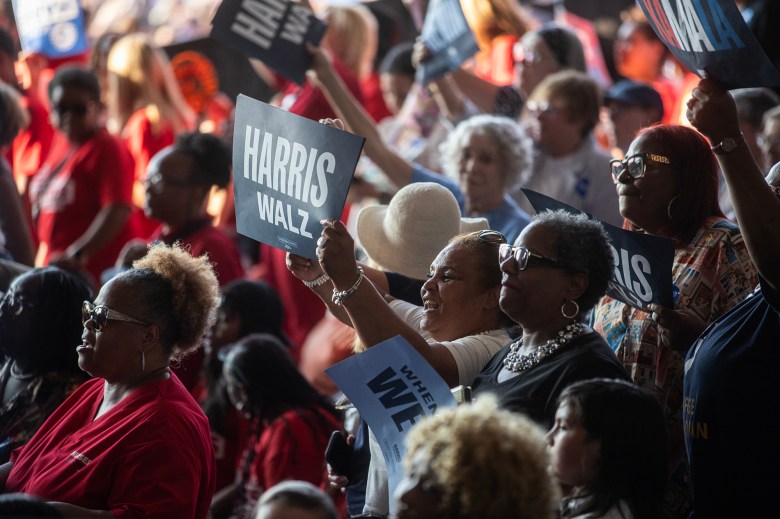 A crowd of supporters cheers and holds placards with 