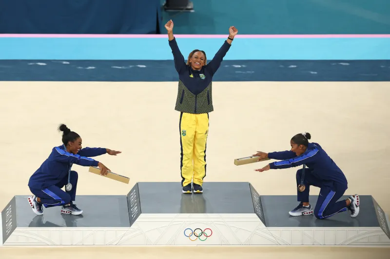 Gymnasts Simone Biles and Jordan Chiles of the United States bow to Rebeca Andrade of Brazil after she won the gold medal in the women’s floor exercise final at the Paris Olympics on Aug. 5.