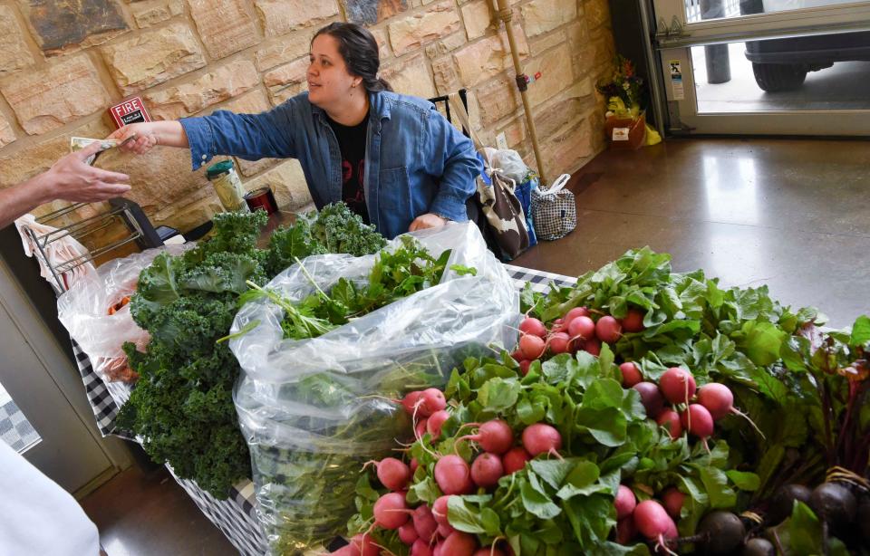 April 20, 2024; Tuscaloosa, AL, USA; Patrons peruse the produce and other products at the Tuscaloosa Farmers Market Saturday at Tuscaloosa River Market. Isabella Garrison gives change to a patron who made a purchase from her booth.