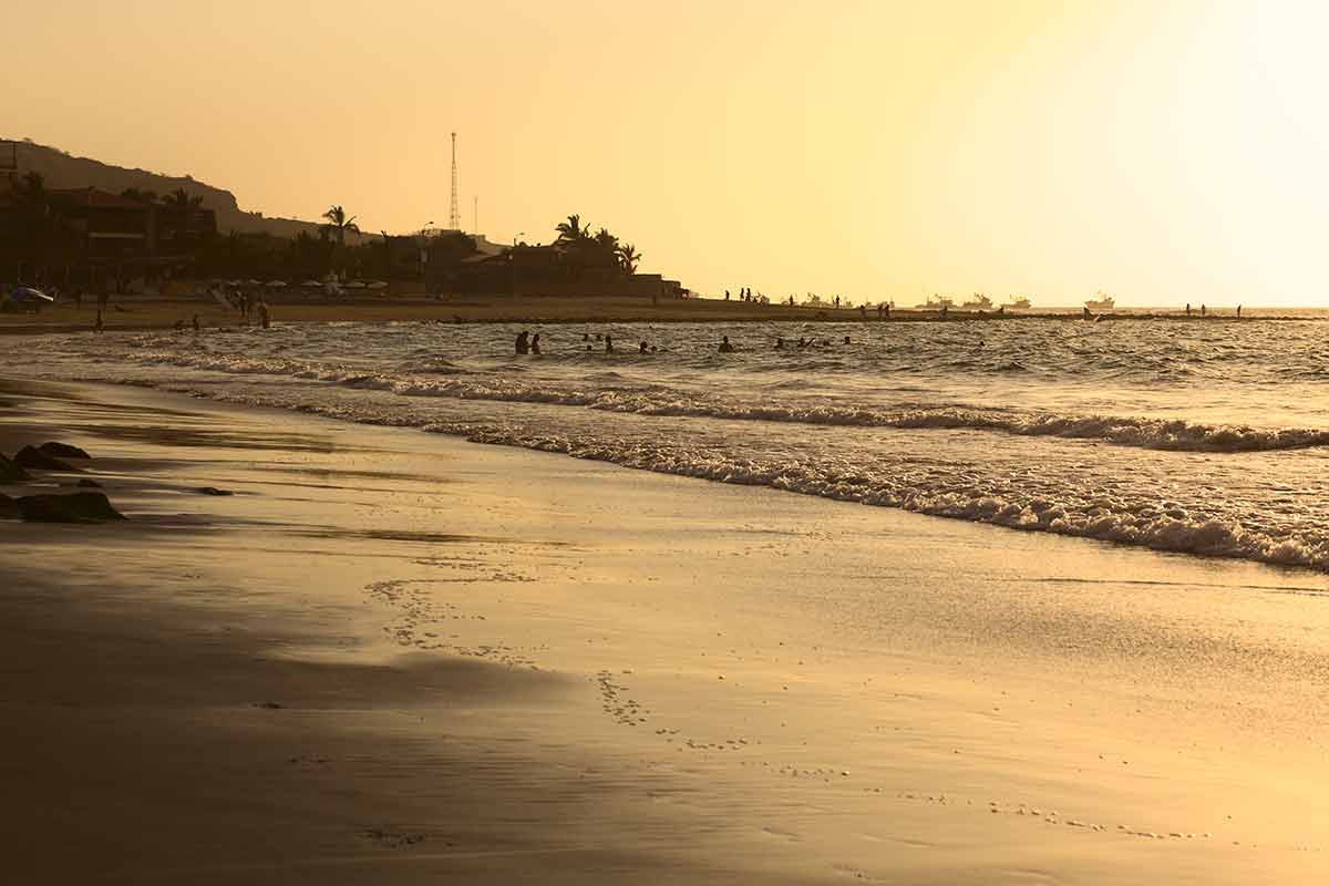 beaches in south america people on the beach and in the water in the light of the setting sun