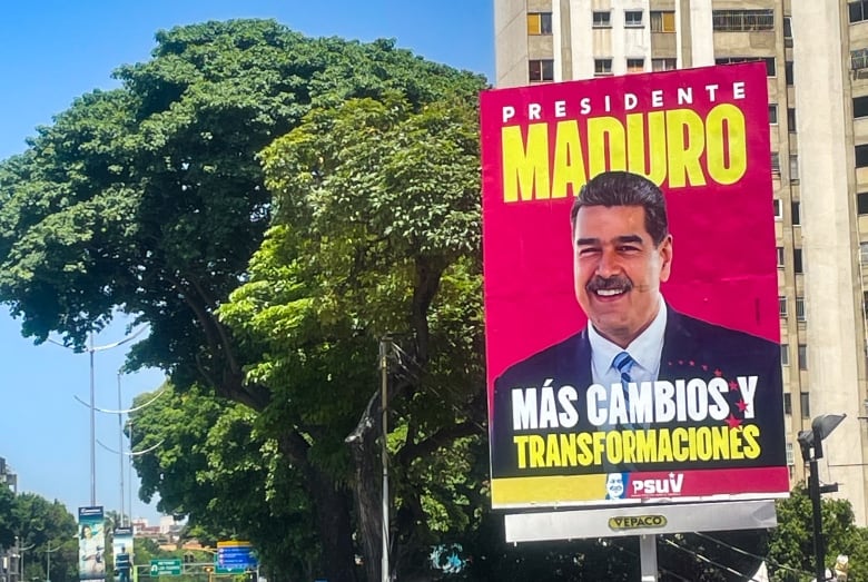 A large poster of a smiling man in a suit hangs on a sunny day.