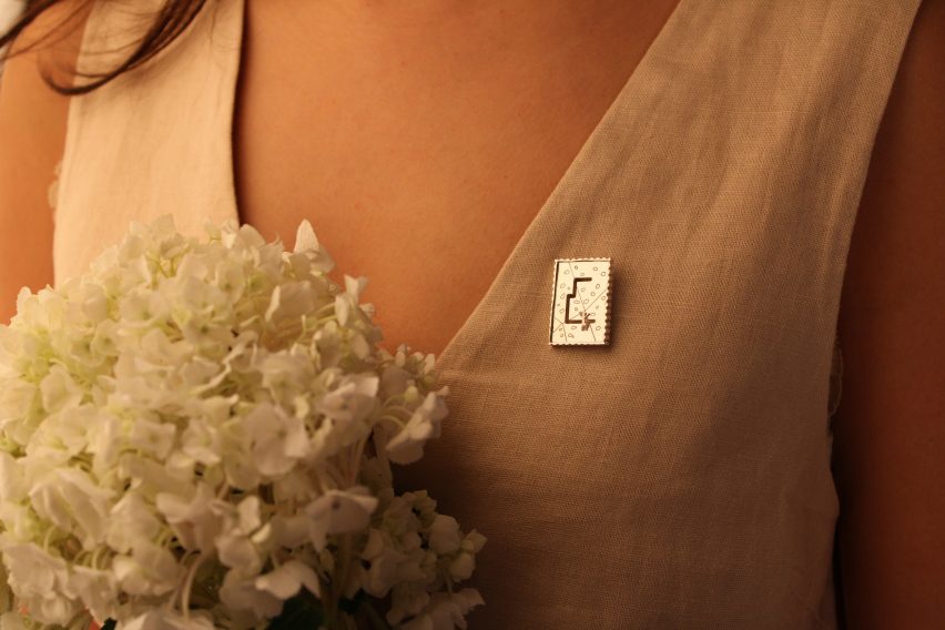 A photograph of a silver rectangular pin attached to a person's shirt.