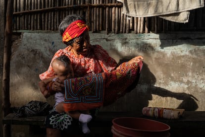 Altagracia holds up one of her traditional mola textiles in front of her home on the island of Gardi Sugdub.