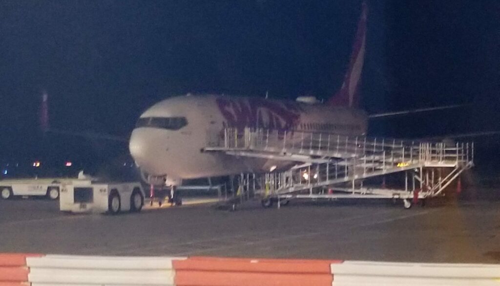 A Swoop 737 is parked, with an air stairs attached for boarding.