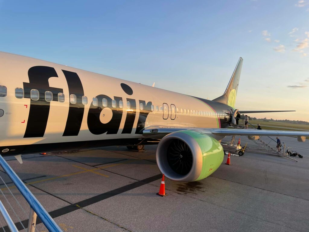Flair Airlines aircraft parked with passengers enter via a staircase at the back entrance. International