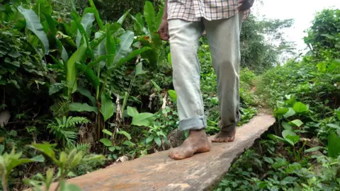 A man walks barefoot across a plank