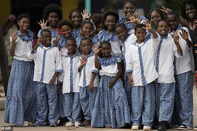 Members of a children's choir wave as they wait for the arrival of Prince Harry and Meghan