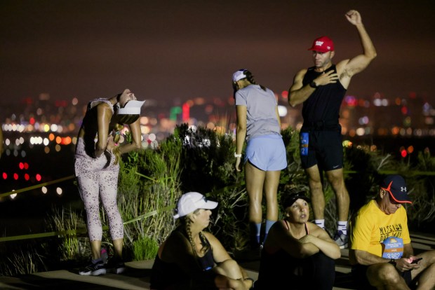 With an early morning view of the downtown San Diego skyline, half marathon runners Shannon Cutt, left, Theresa Staine, and Matt Daly stretch before a 6:15 am start time at Cabrillo National Monument during the 47th annual America's Finest City Half Marathon and 5K in San Diego on Sunday, Aug. 18, 2024. Over 1,300 people participated in the 5K and more than 4,300 in the half marathon. (Hayne Palmour IV / For The San Diego Union-Tribune)