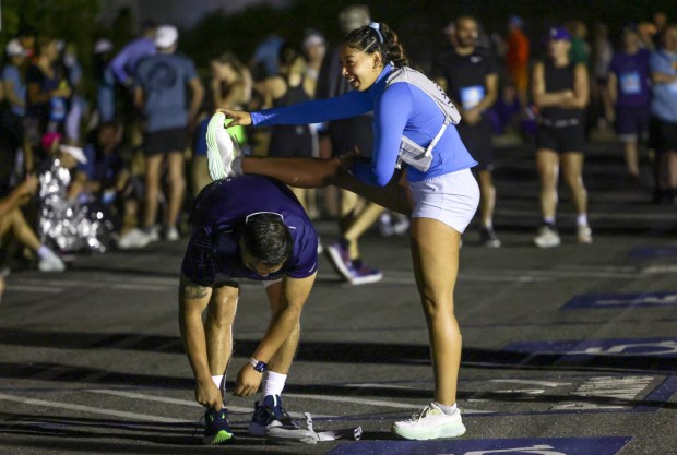 Chloe Wiley uses the back of Brayan Campos to stretch her leg before a 6:15 am start time at Cabrillo National Monument during the 47th annual America's Finest City Half Marathon and 5K in San Diego on Sunday, Aug. 18, 2024. Over 1,300 people participated in the 5K and more than 4,300 in the half marathon. (Hayne Palmour IV / For The San Diego Union-Tribune)