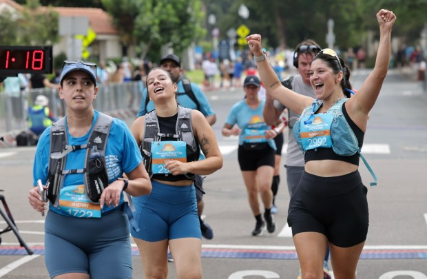 Half marathon runners celebrate as they cross the finish line in Balboa Park during the 47th annual America's Finest City Half Marathon and 5K in San Diego on Sunday, Aug. 18, 2024. Over 1,300 people participated in the 5K and more than 4,300 in the half marathon. (Hayne Palmour IV / For The San Diego Union-Tribune)