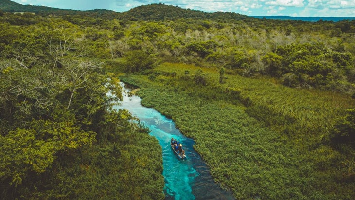 The Rio Sucuri cuts through a swath of vibrant-green jungle in Brazil. A group makes its way upstream in a canoe.