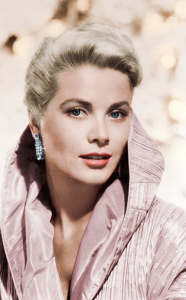 Grace Kelly poses in an elegant, high-collared outfit with sparkling earrings, and a styled hairdo