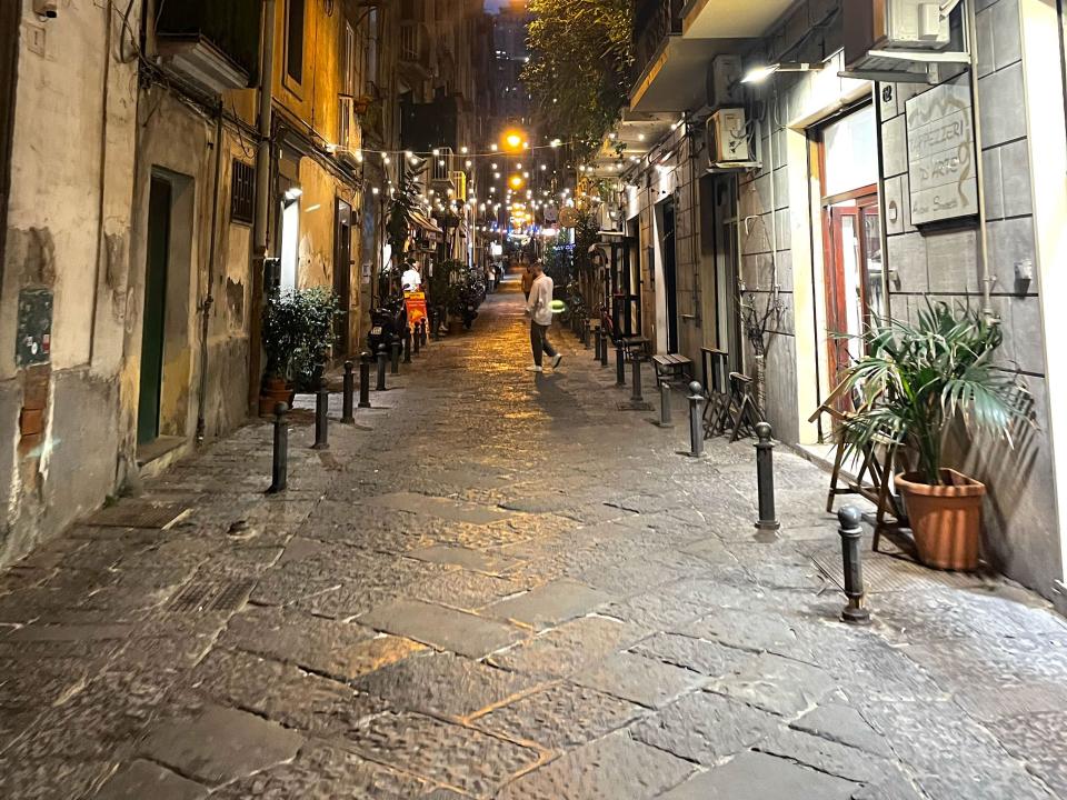 A cobblestone street in Italy at night.