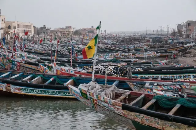 Narrow, canoe-style fishing boats - wey pipo sabi locally as pirogues - dey close to di shore for Saint-Louis, Senegal.