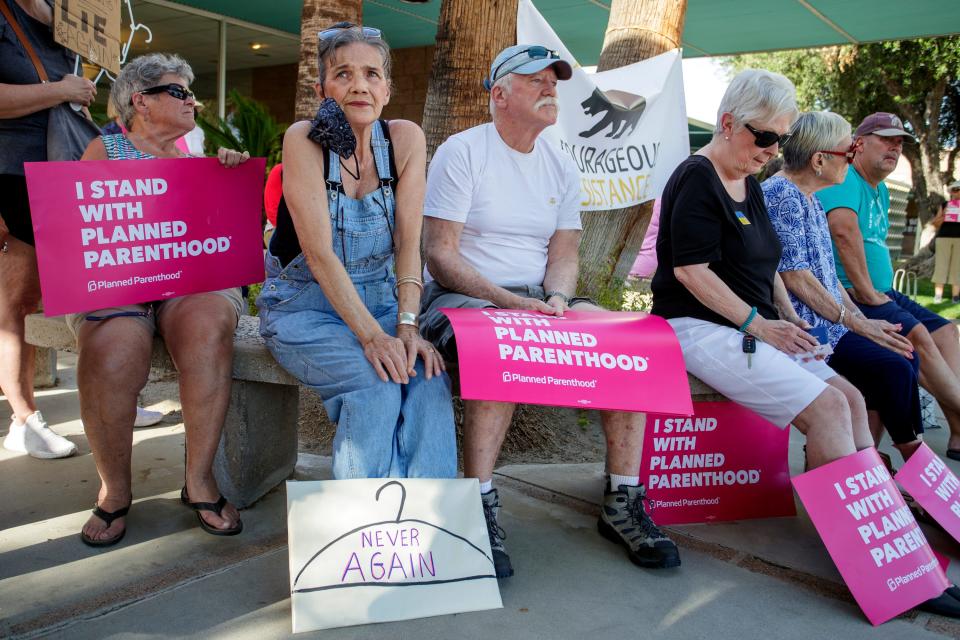 Deborah Fischer, center, sits with a sign at her feet during a rally outside City Hall in Palm Springs, Calif., on Tuesday, May 3, 2022, over concerns that the Supreme Court's 1973 ruling of Roe Vs. Wade could be overturned. The landmark decision gave pregnant women a new constitutional right to choose abortion. 