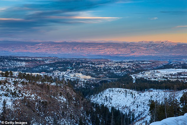 Above, a bucolic winter image surveying Los Alamos, New Mexico on the left and center, the Omega Bridge in the middle and the Los Alamos National Laboratories on the right