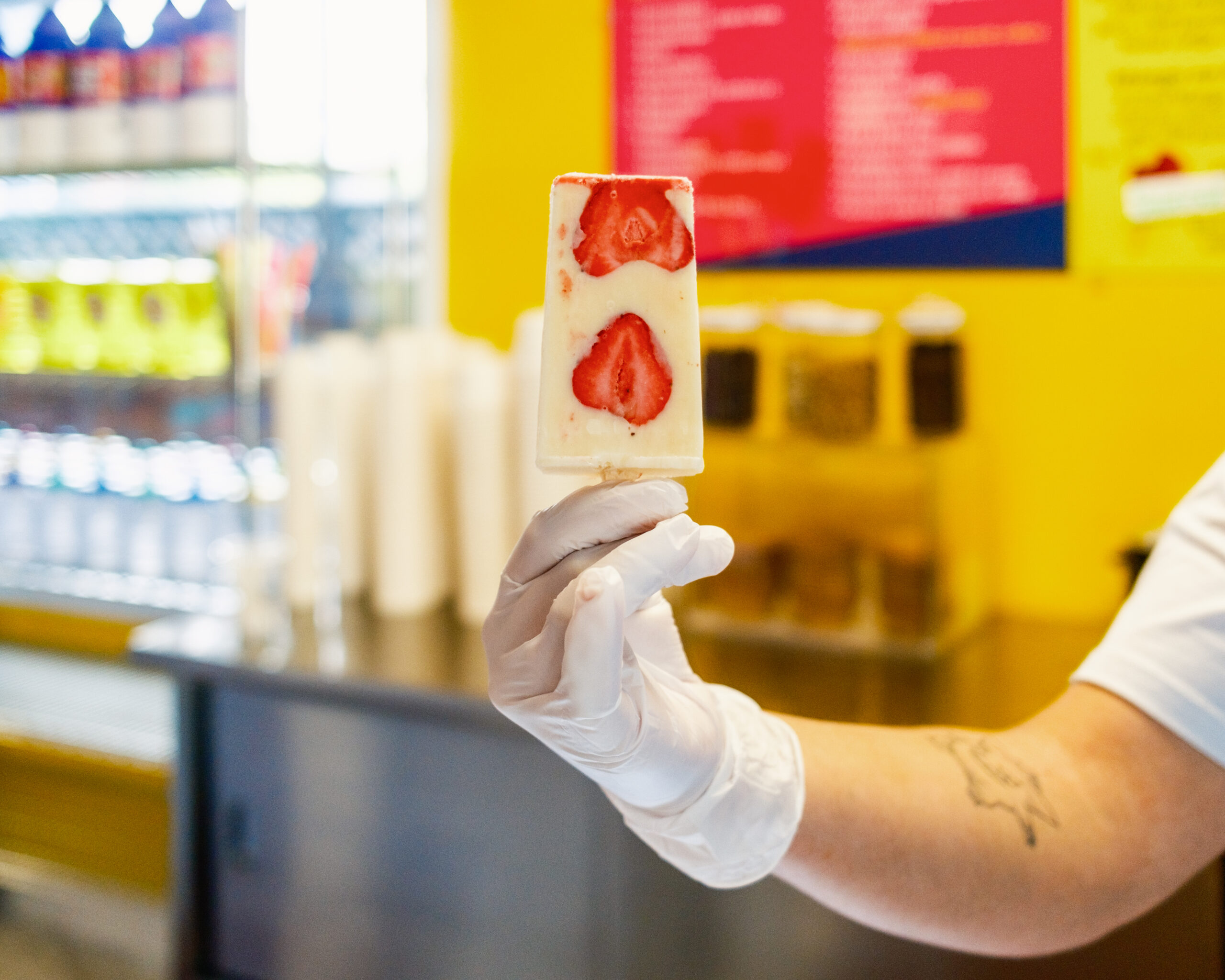 a person holds up strawberry paleta