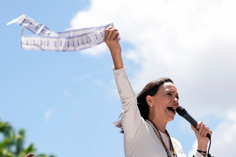 Opposition leader Maria Corina Machado displays vote tally sheets during a protest against the reelection of President Nicolás Maduro one month after the disputed presidential vote which she says the opposition won by a landslide, in Caracas, Venezuela, Wednesday, Aug. 28, 2024.