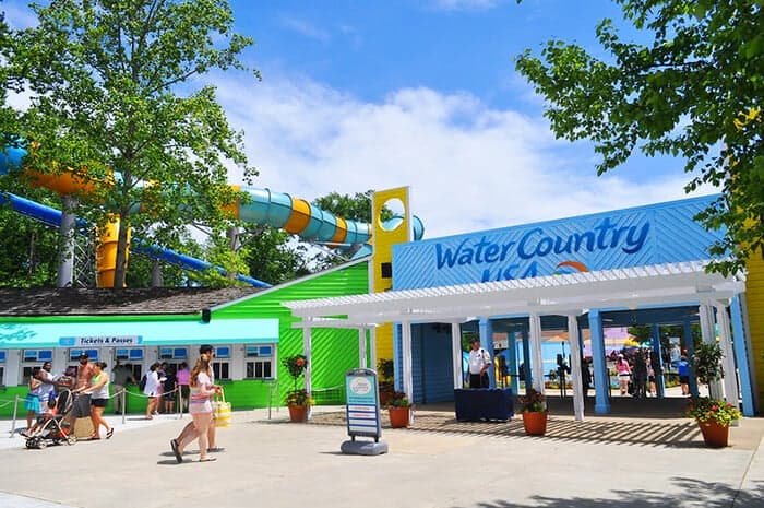 People standing near the entrance of Water Country USA, with colorful buildings and a waterslide visible in the background.