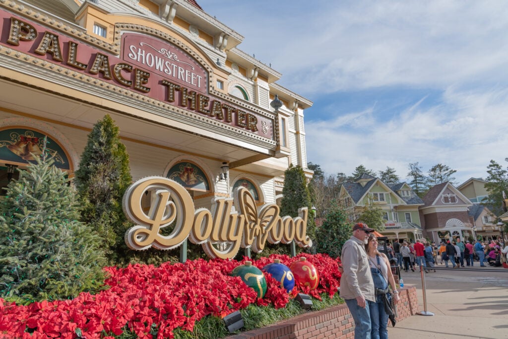 Visitors outside the Showstreet Palace Theater at Dollywood Theme Park, decorated with red poinsettias and Christmas ornaments.