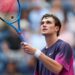 Jack Draper raises his racket at the US Open tennis, wearing a purple Nike t-shirt.