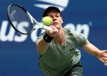 Jannik Sinner plays a forehand return at the US Open 2024 in a khaki t-shirt.