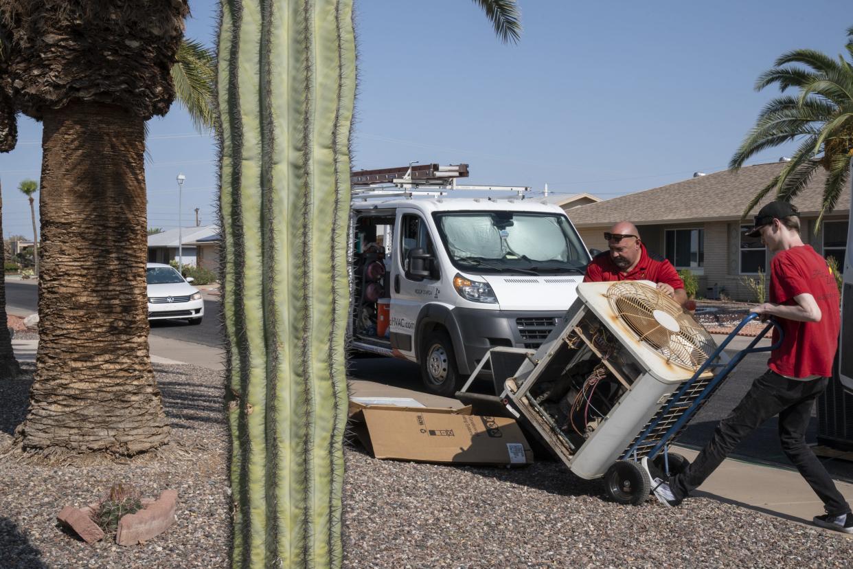 Gerald Sandoz (left) and Patrick Woods of AirZona HVAC Inc remove an old AC unit on July 23, 2024, at a home in Sun City.