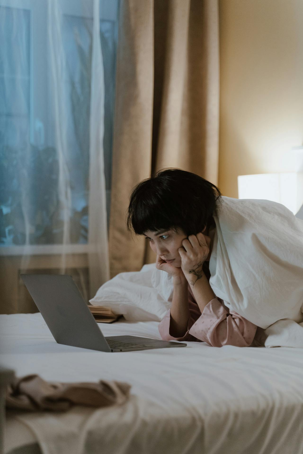 woman looks at laptop on bed